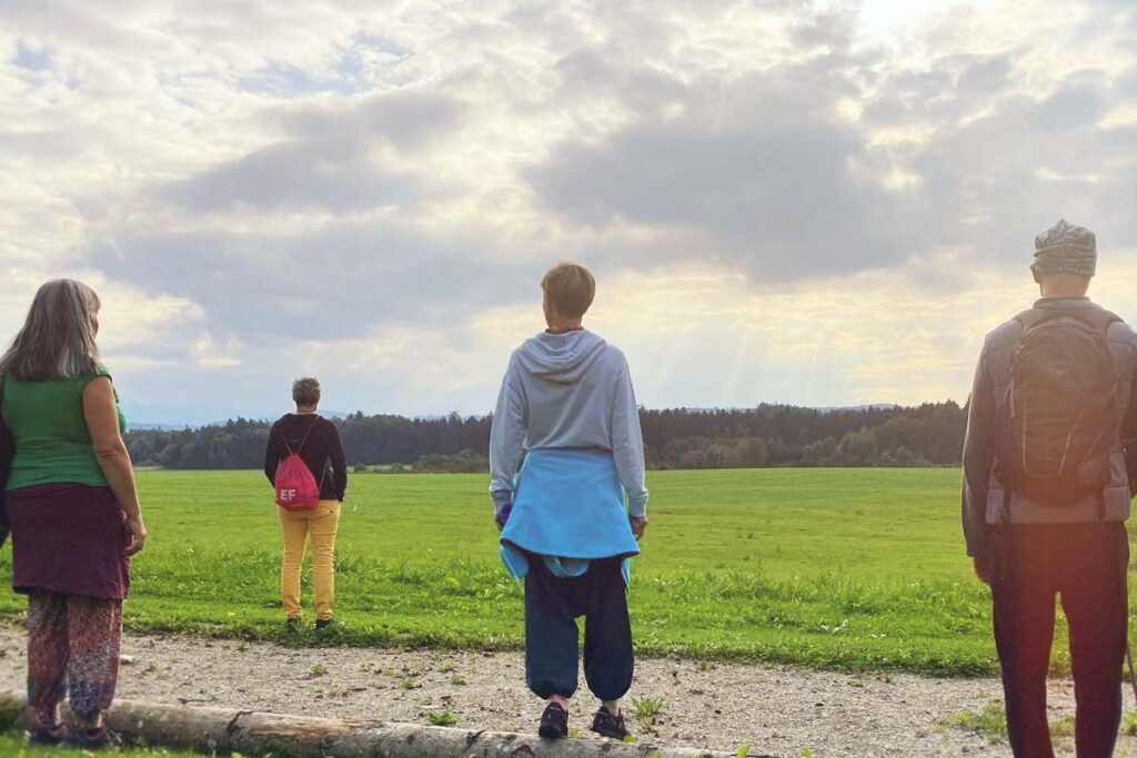 4 Personen stehen versetzt und blicken nach vorn zur Sonne